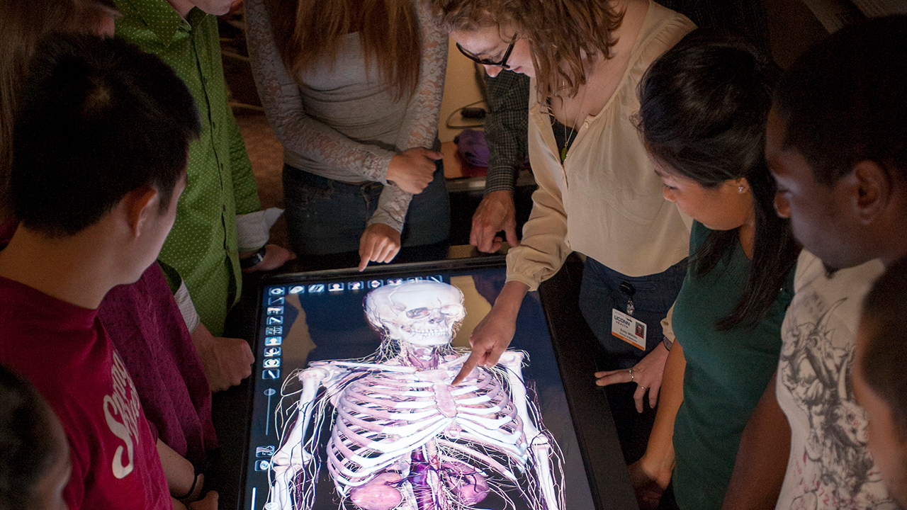 Medical students gather around a 3D digital touch screen anatomy table in the virtual anatomy lab at UConn Health