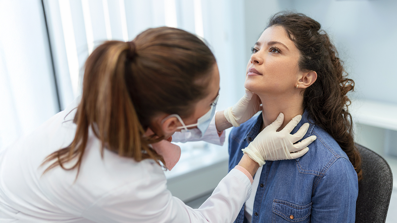 A doctor examining a patient's tonsils in an exam room