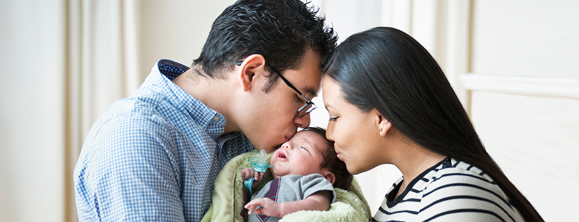 parents kissing newborn