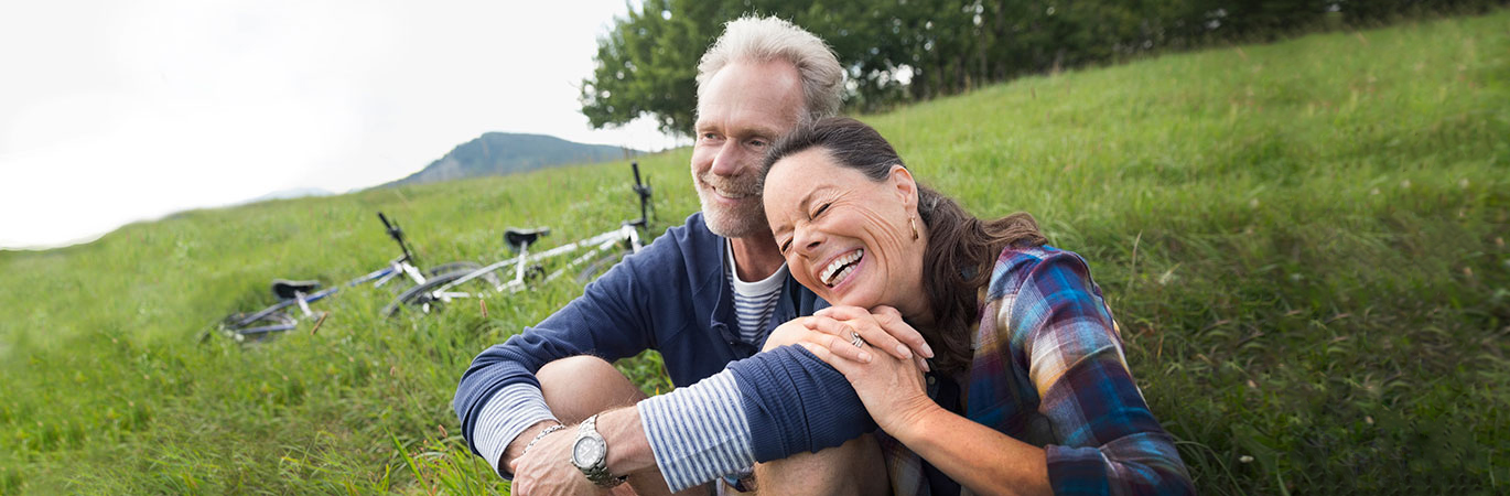 Joyful man and woman rest on a hill after biking