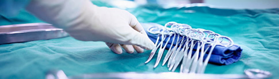 Gloved surgeon's hand reaching for clamps