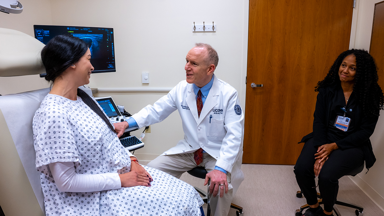 Chair of the Department of Surgery Kevin Staveley-O'Carroll, MD, PhD, and nurse Tara meet with a patient in an exam room