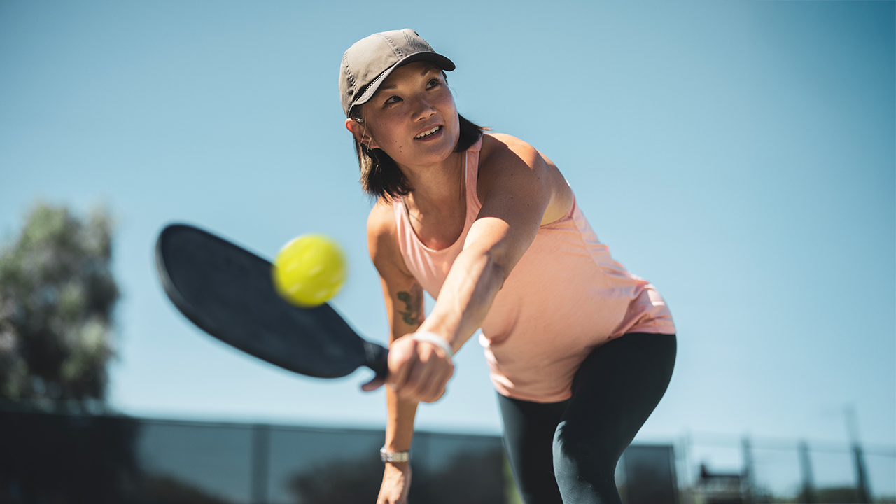Woman playing pickleball ready to return the ball with her backhand