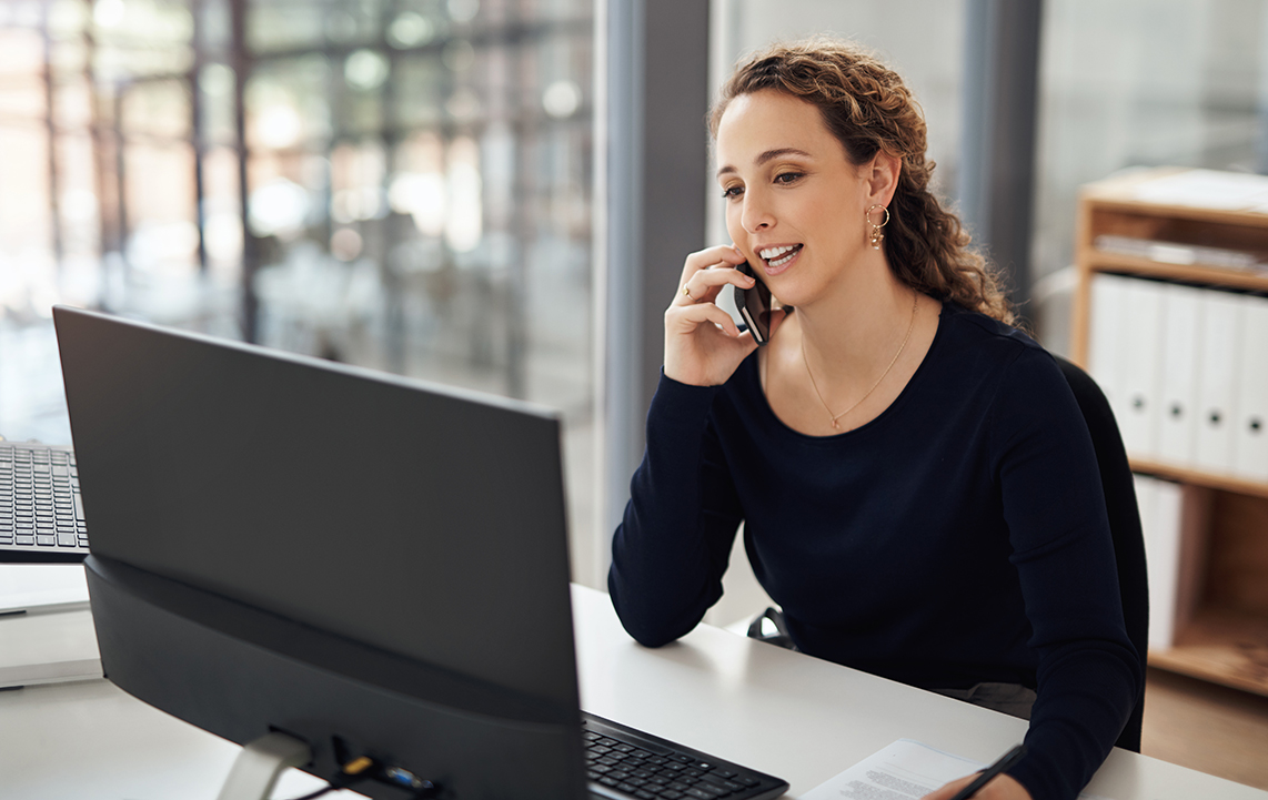 Woman talking on her cell phone with her laptop open in front of her