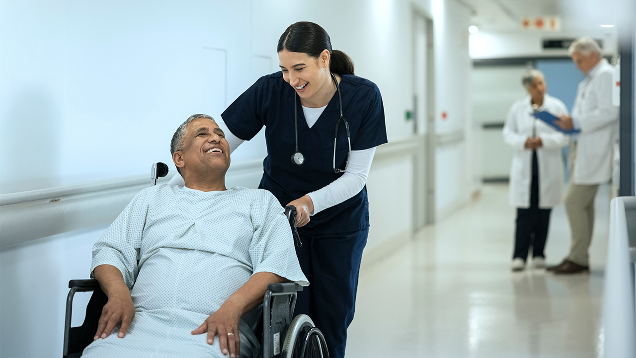 A nurse pushing a patient in a wheelchair down a hospital hallway