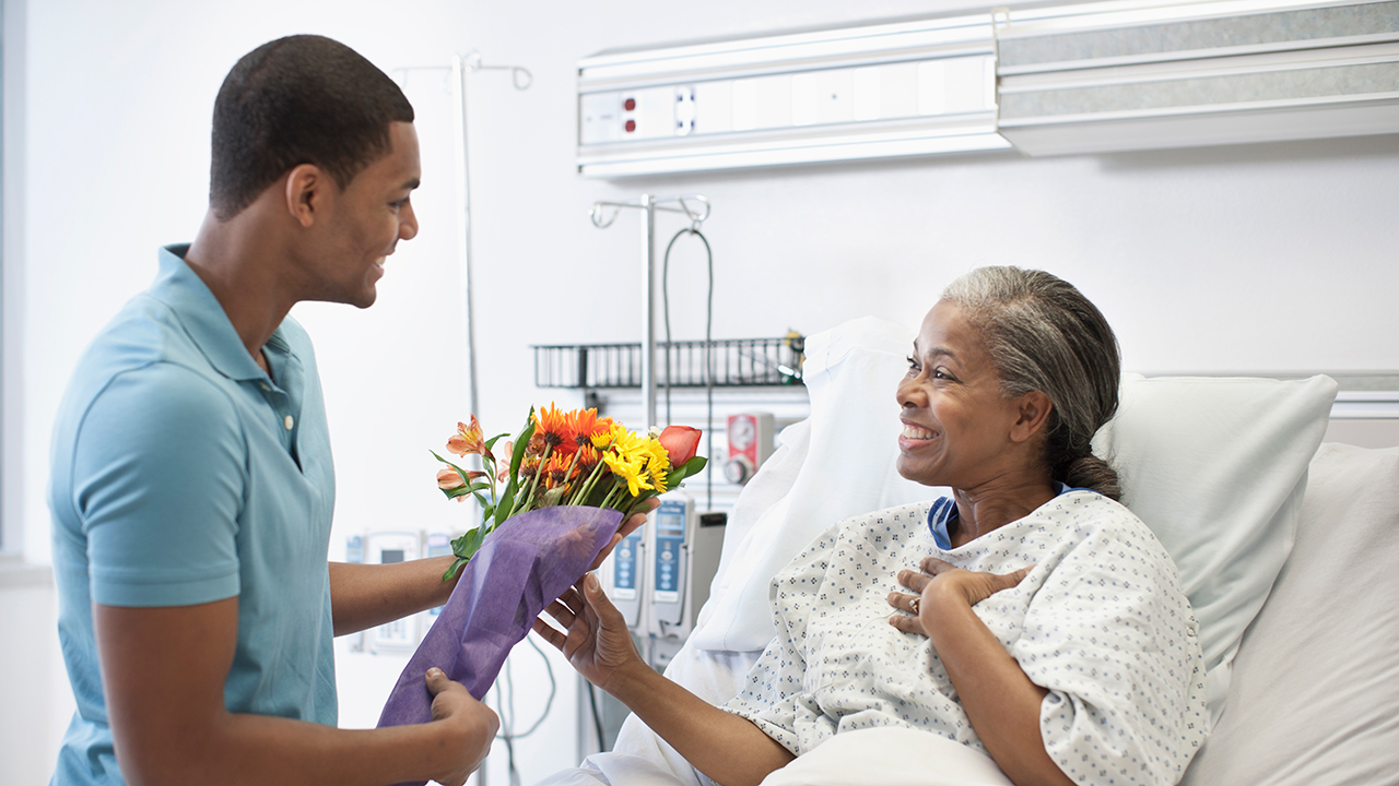 A son bringing his mother flowers in hospital