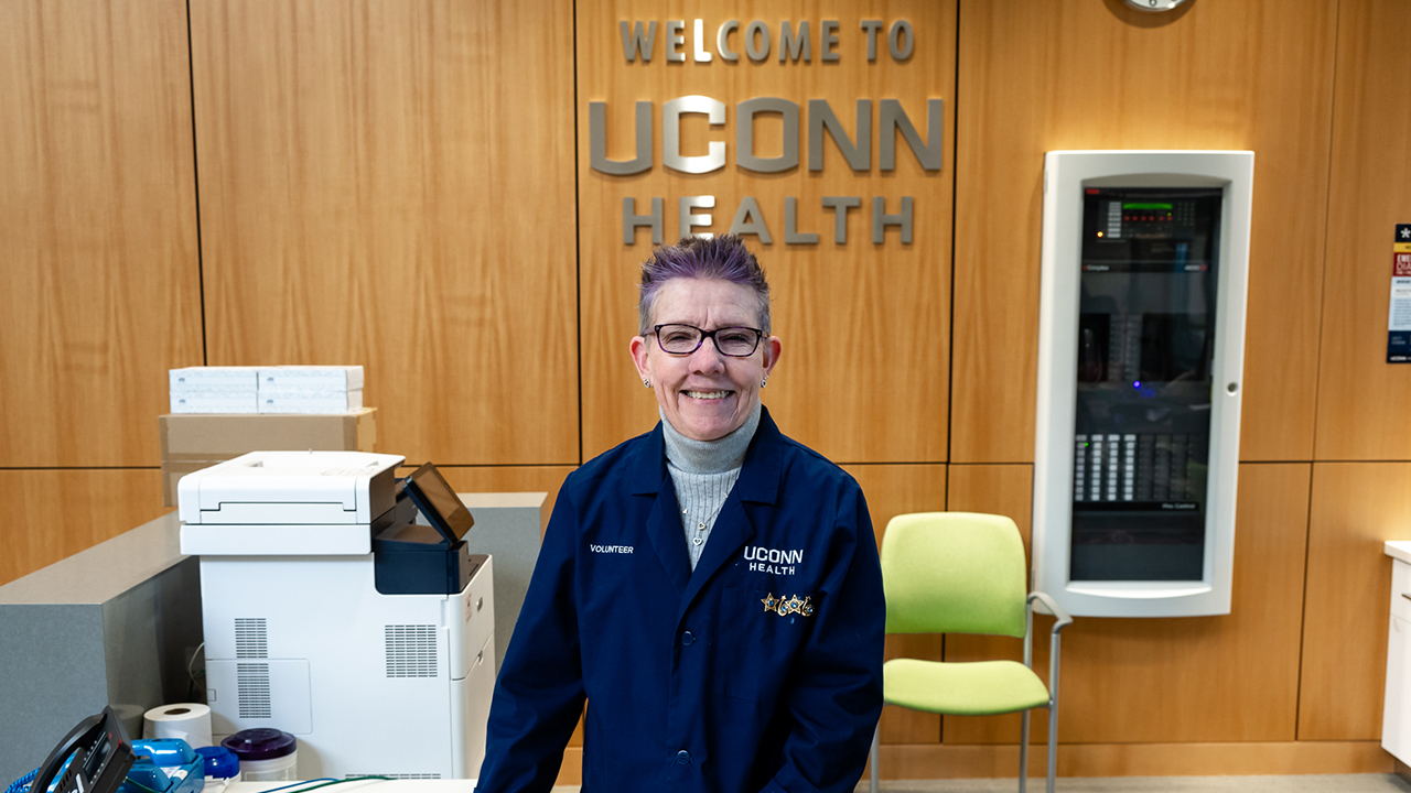 Joan Monroe, a UConn Health volunteer, standing at the Information Desk in the hospital lobby